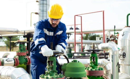 Worker turning valve on gas plant pipeline